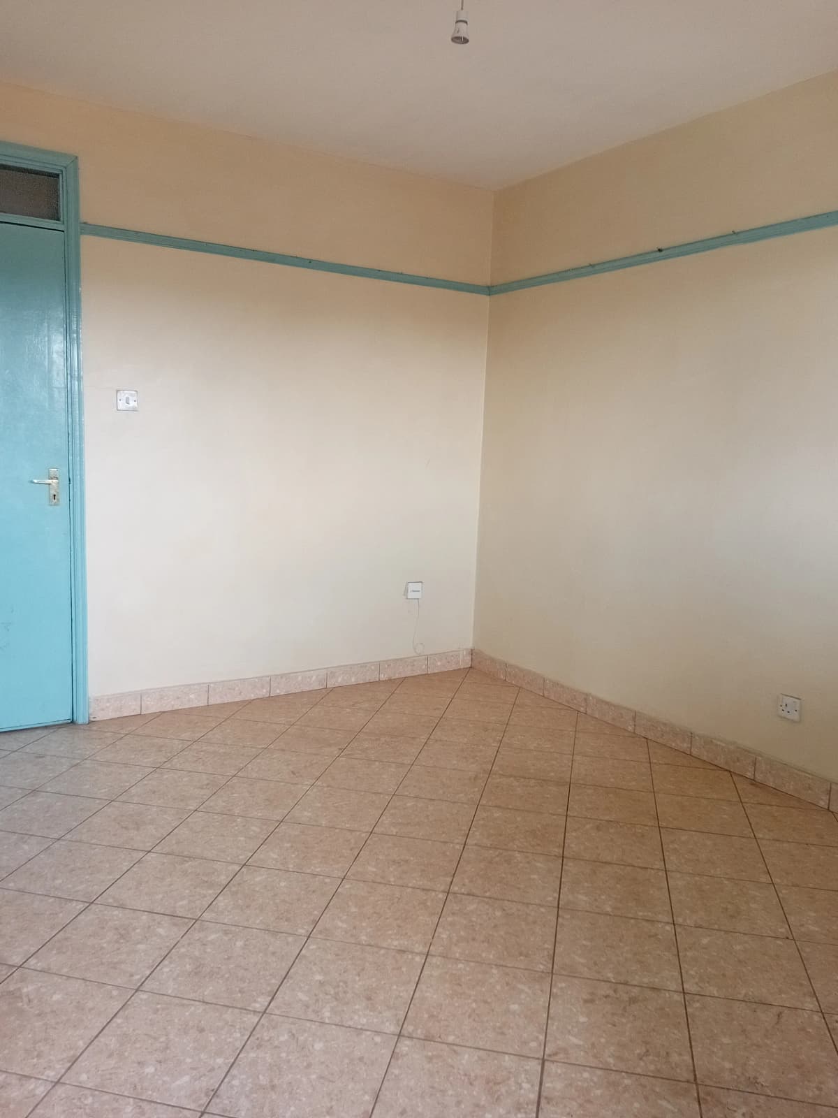 Unfurnished bedroom with terracotta tile flooring and blue door