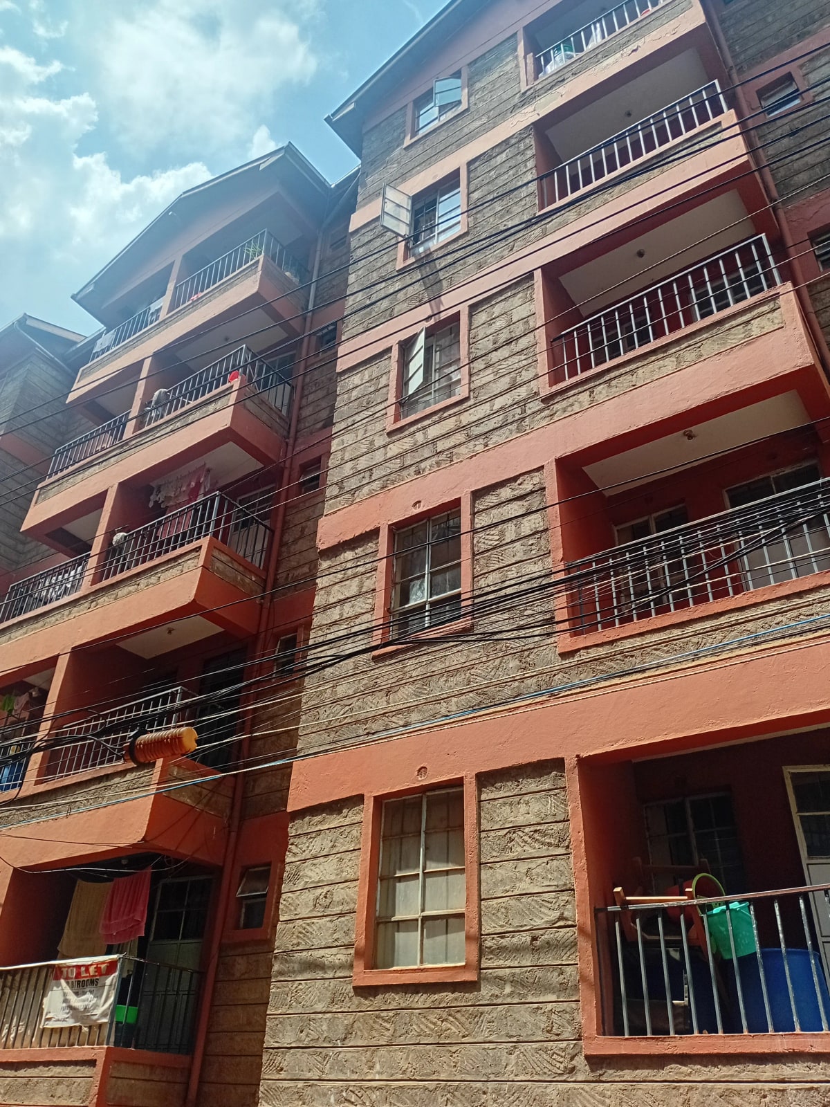 Multi-story residential building facade with red trim and balconies
