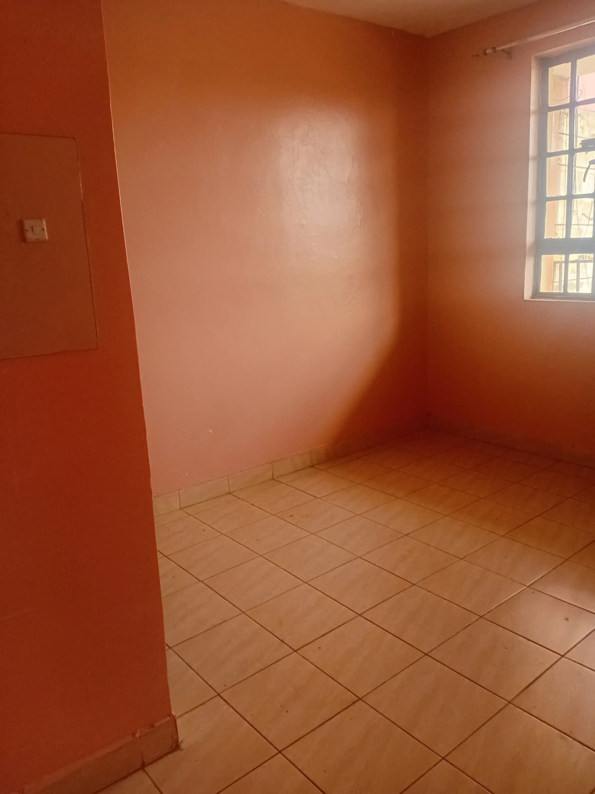 Empty bedroom with terracotta walls and tiled flooring