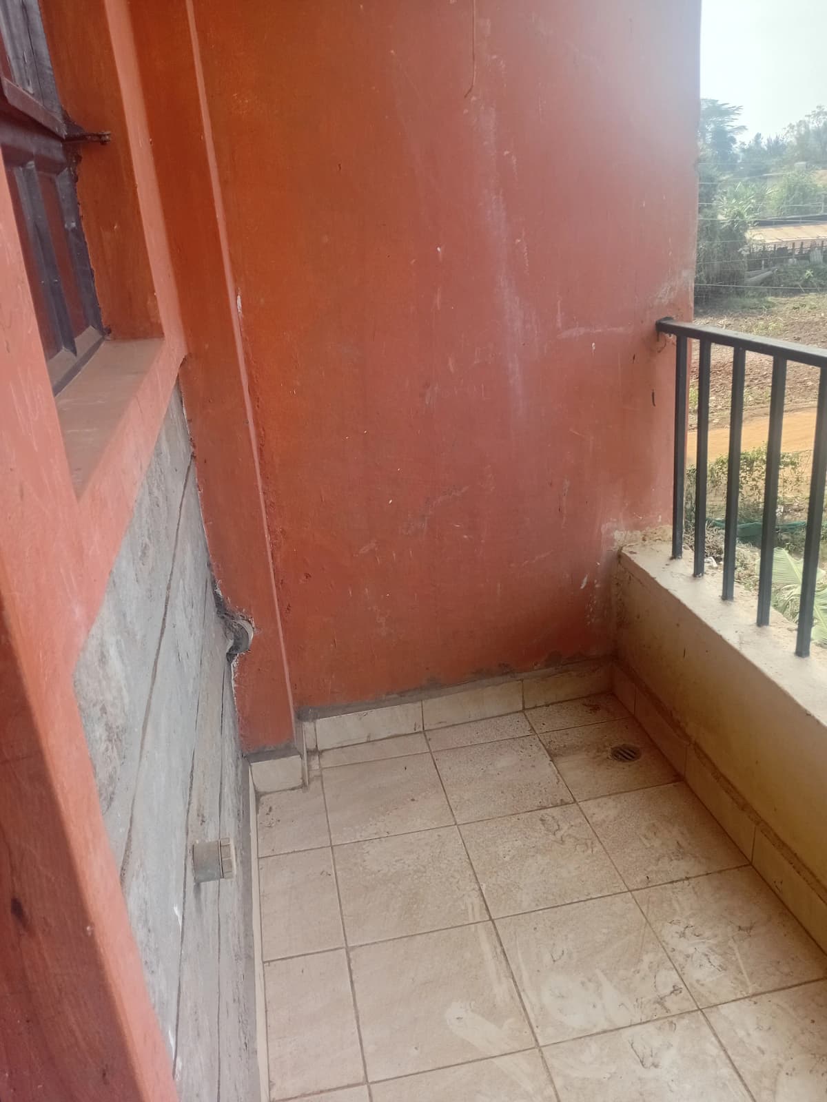 Tiled balcony with metal railing overlooking rural landscape
