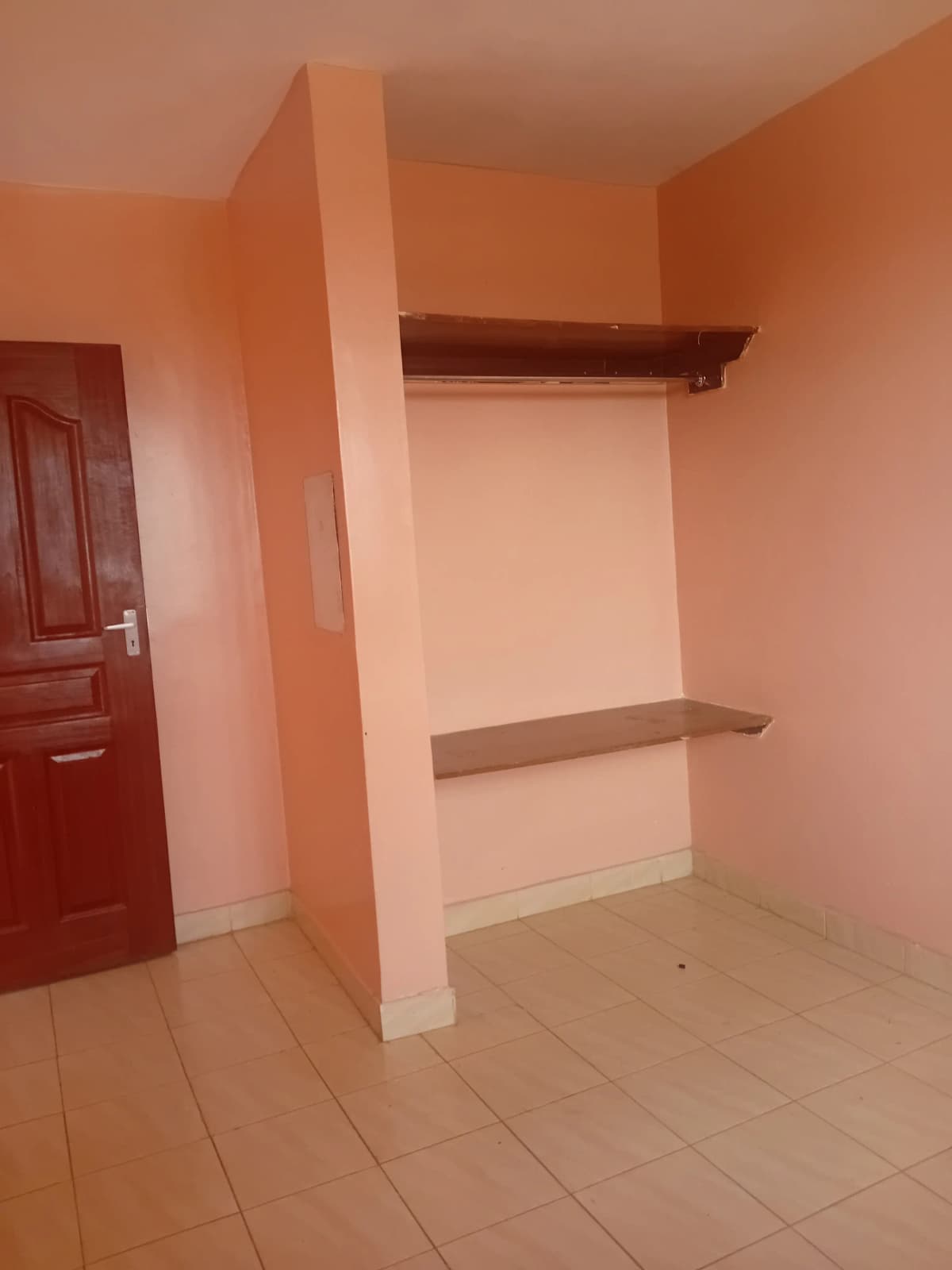 Empty bedroom with built-in shelving and orange accent walls