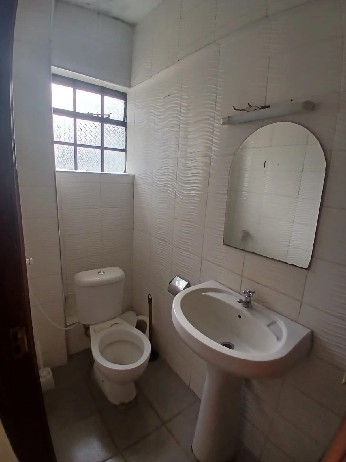Compact bathroom with pedestal sink, toilet, and mirror
