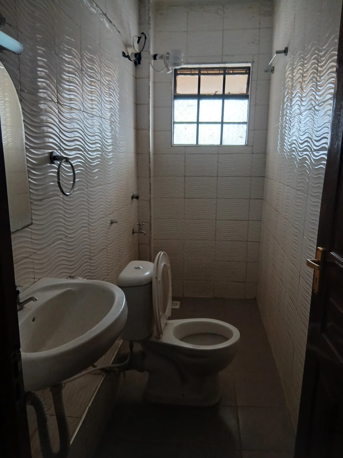 Compact bathroom with toilet, sink, and tiled shower enclosure
