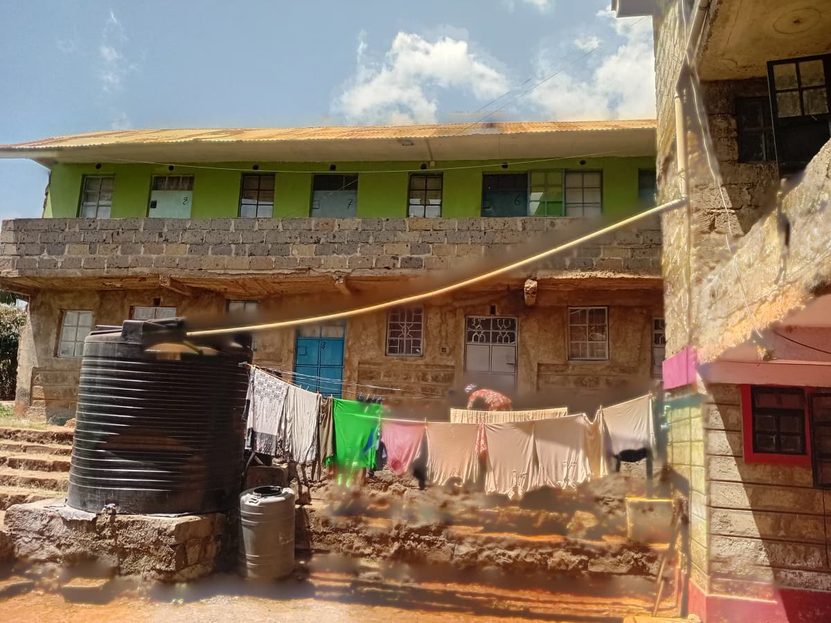 Multi-story residential building with green painted facade and compound