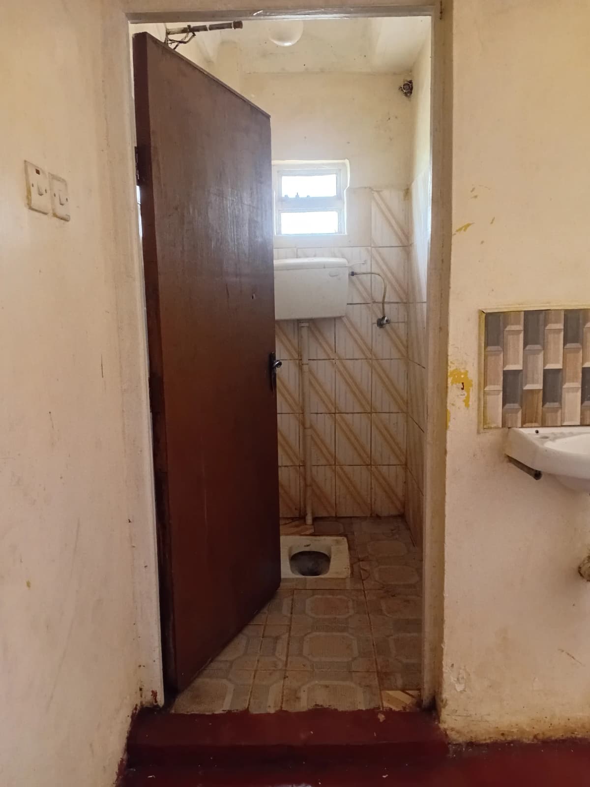 Small bathroom with tiled floor and wooden door