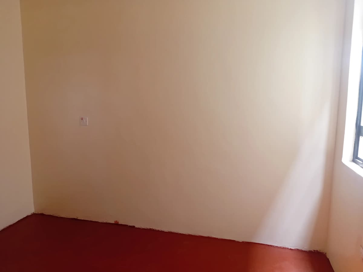 Empty bedroom with red flooring and natural light