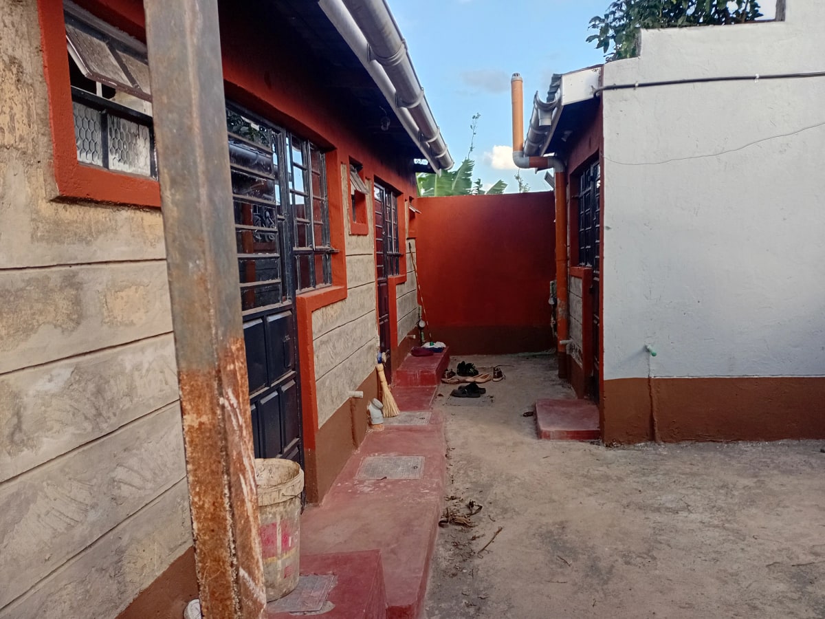 Compound entrance with red gate and single-story residential building