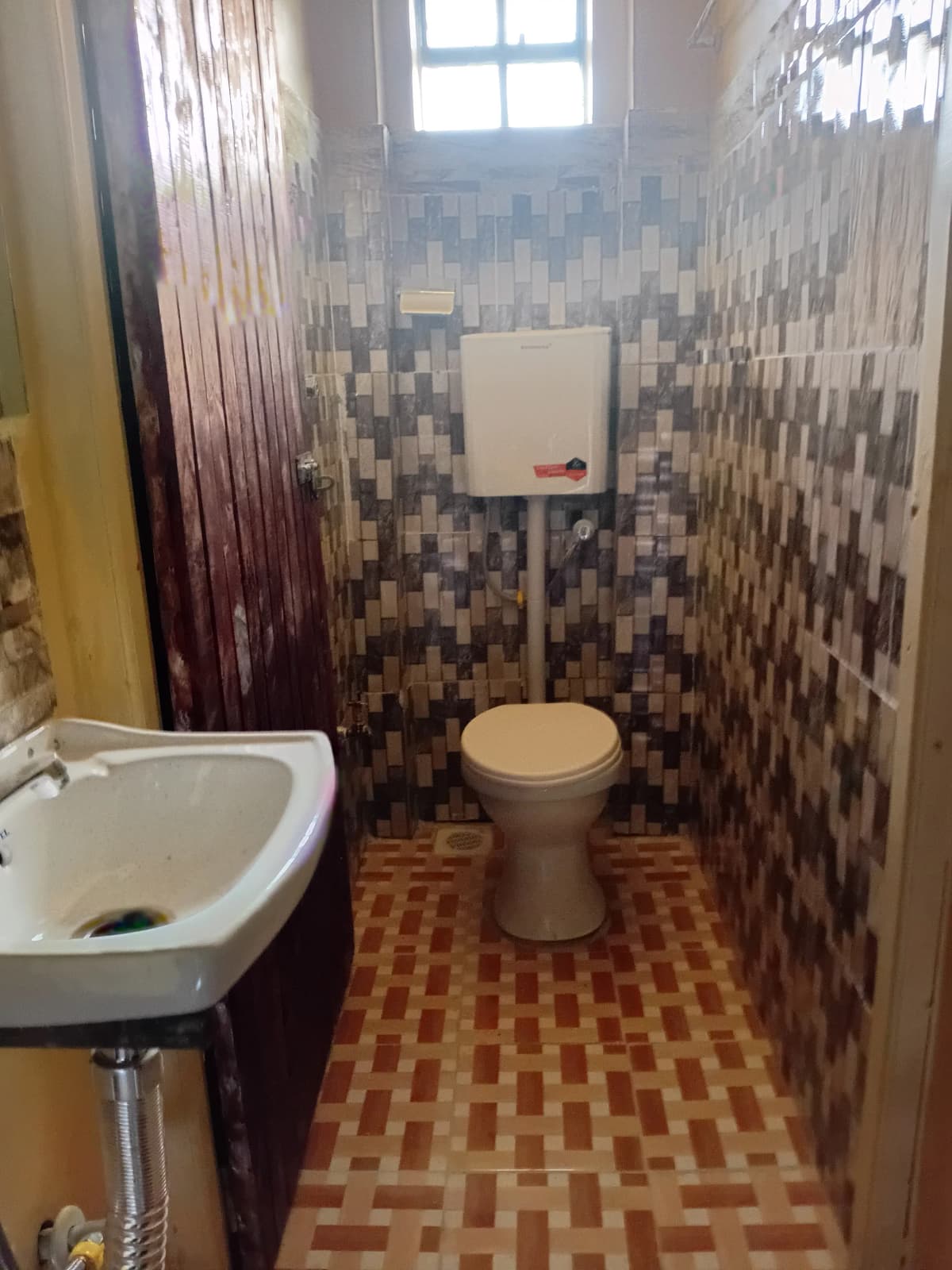 Compact bathroom with mosaic tile walls, toilet, and sink