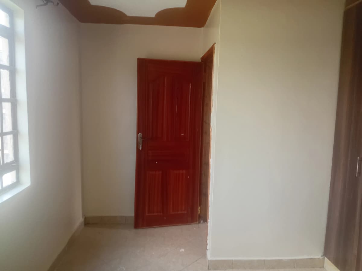 Empty hallway with red door and natural light from window