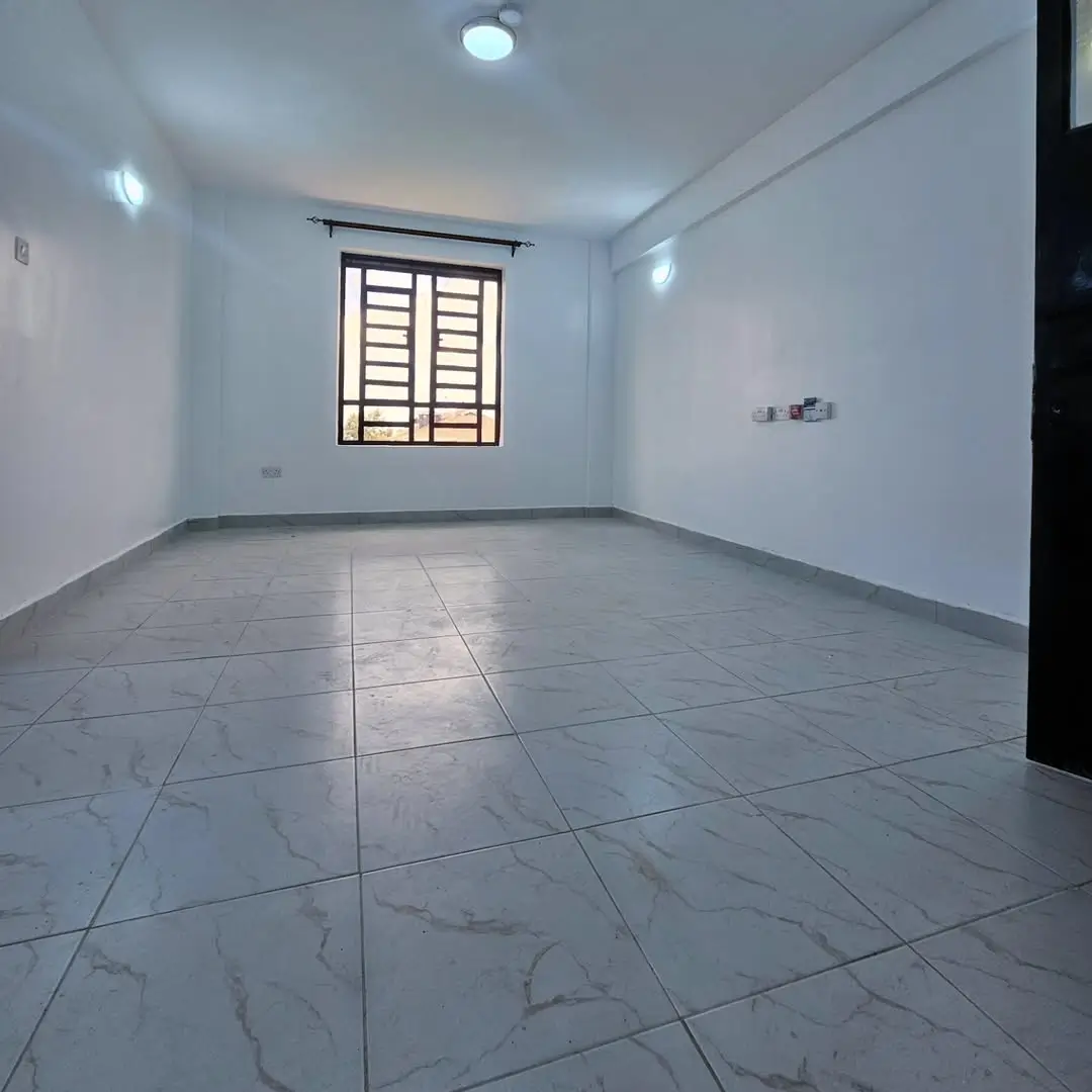 Empty living room with marble-effect tiles and barred window