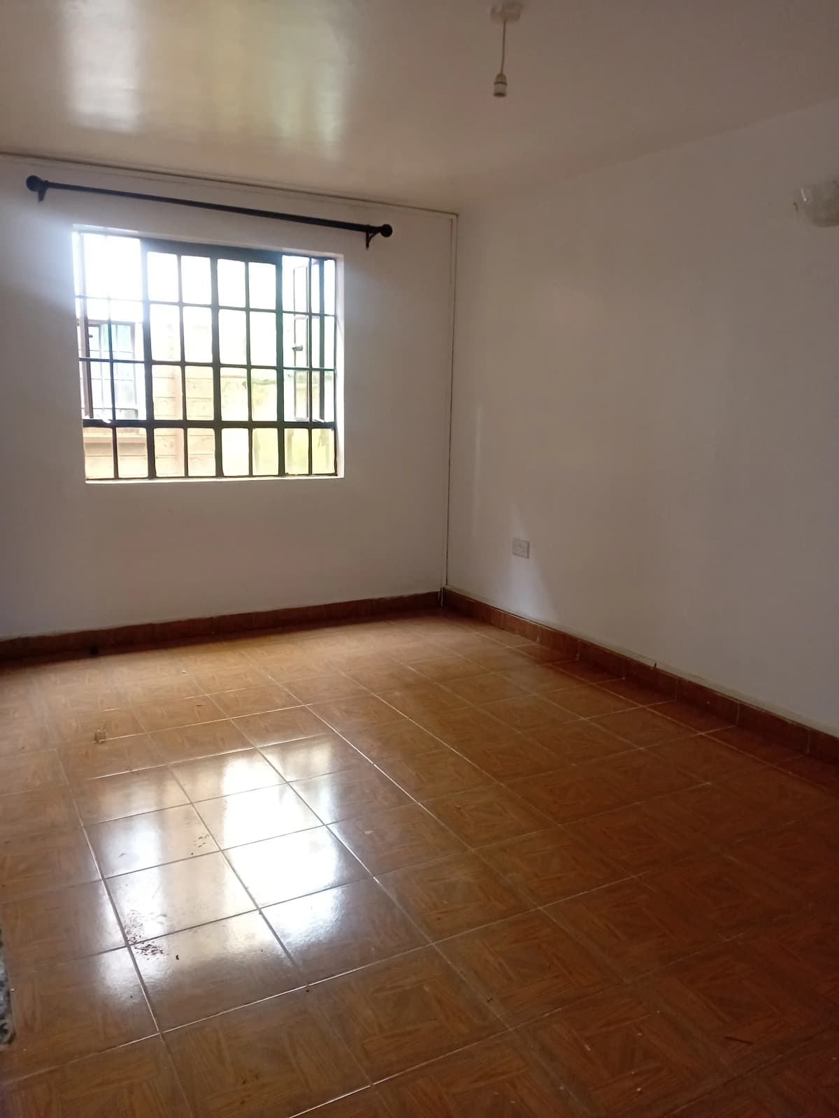Spacious bedroom with wooden flooring and barred window