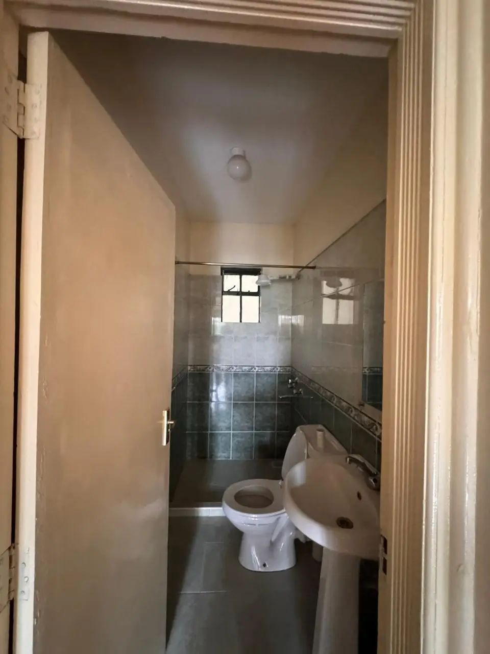 Compact bathroom with toilet, sink, and tiled shower enclosure
