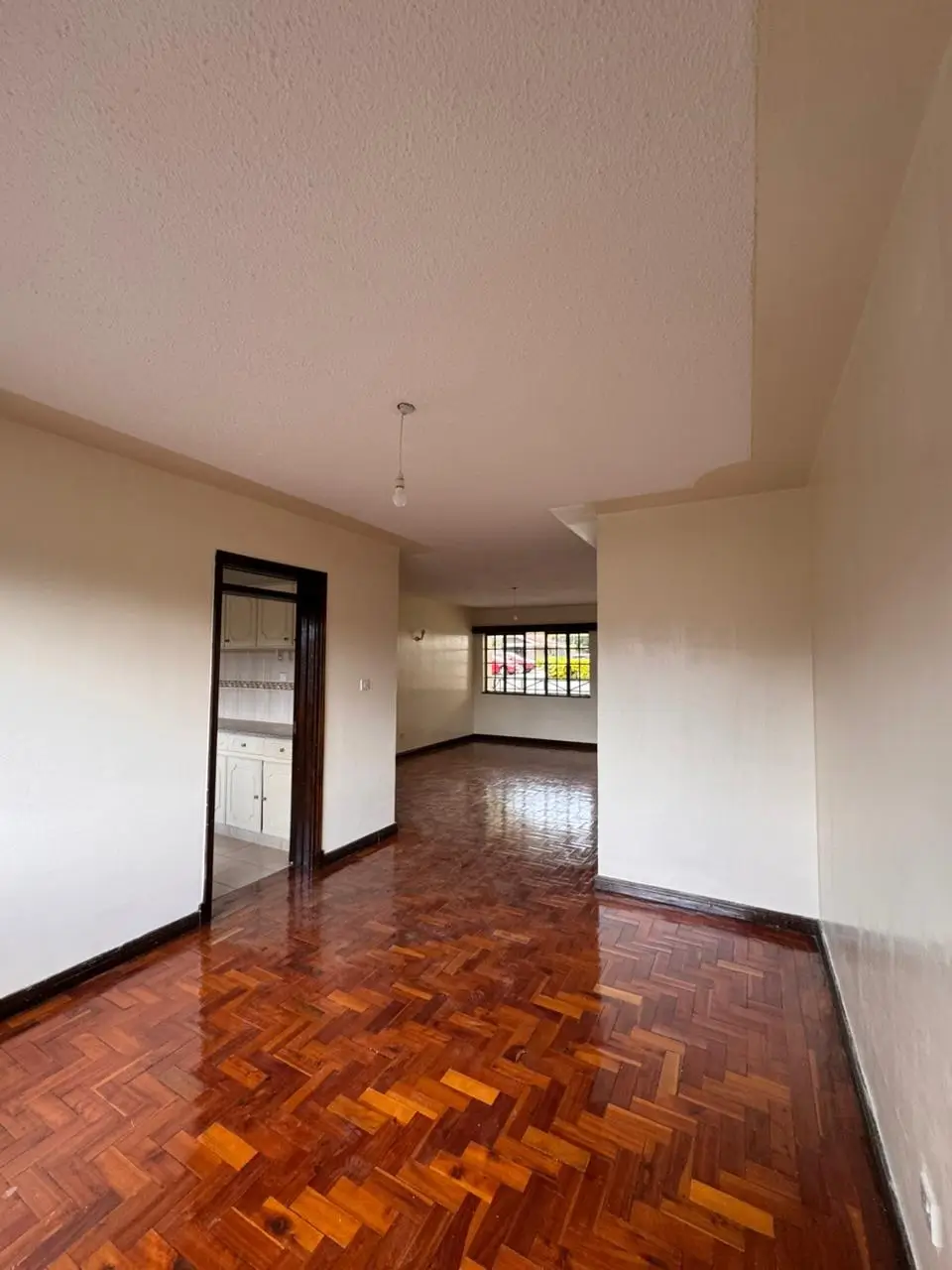 Spacious living room with herringbone wooden flooring and natural light