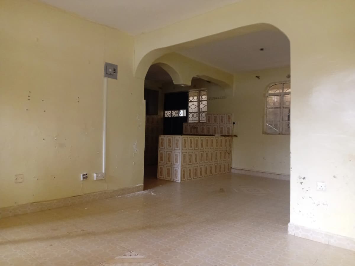Empty living room with archway and cream-colored walls