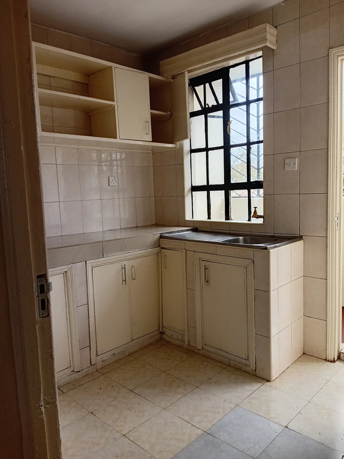 Compact kitchen with cream cabinets, white tile backsplash, window