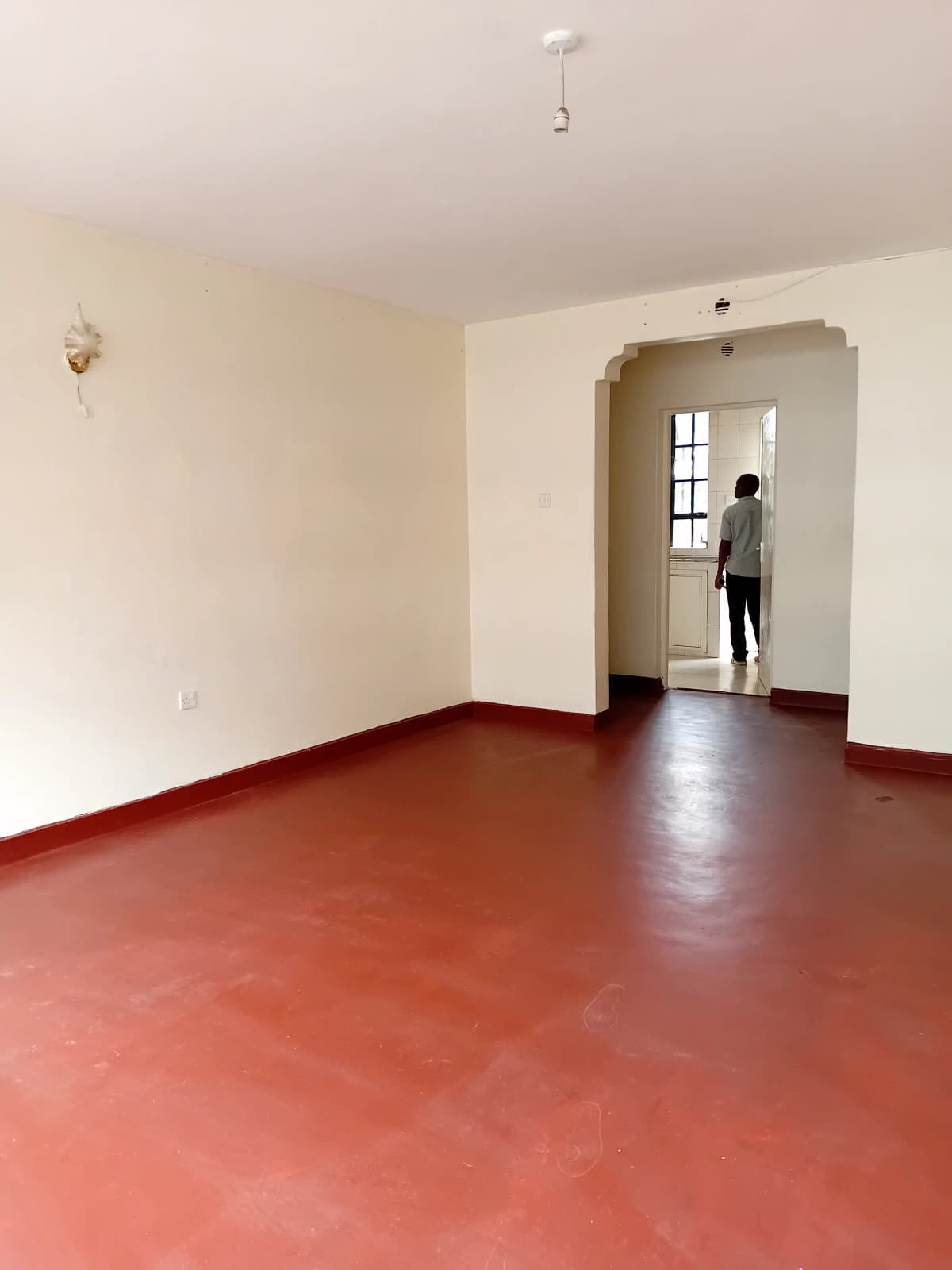 Spacious empty living room with terracotta floor and archway