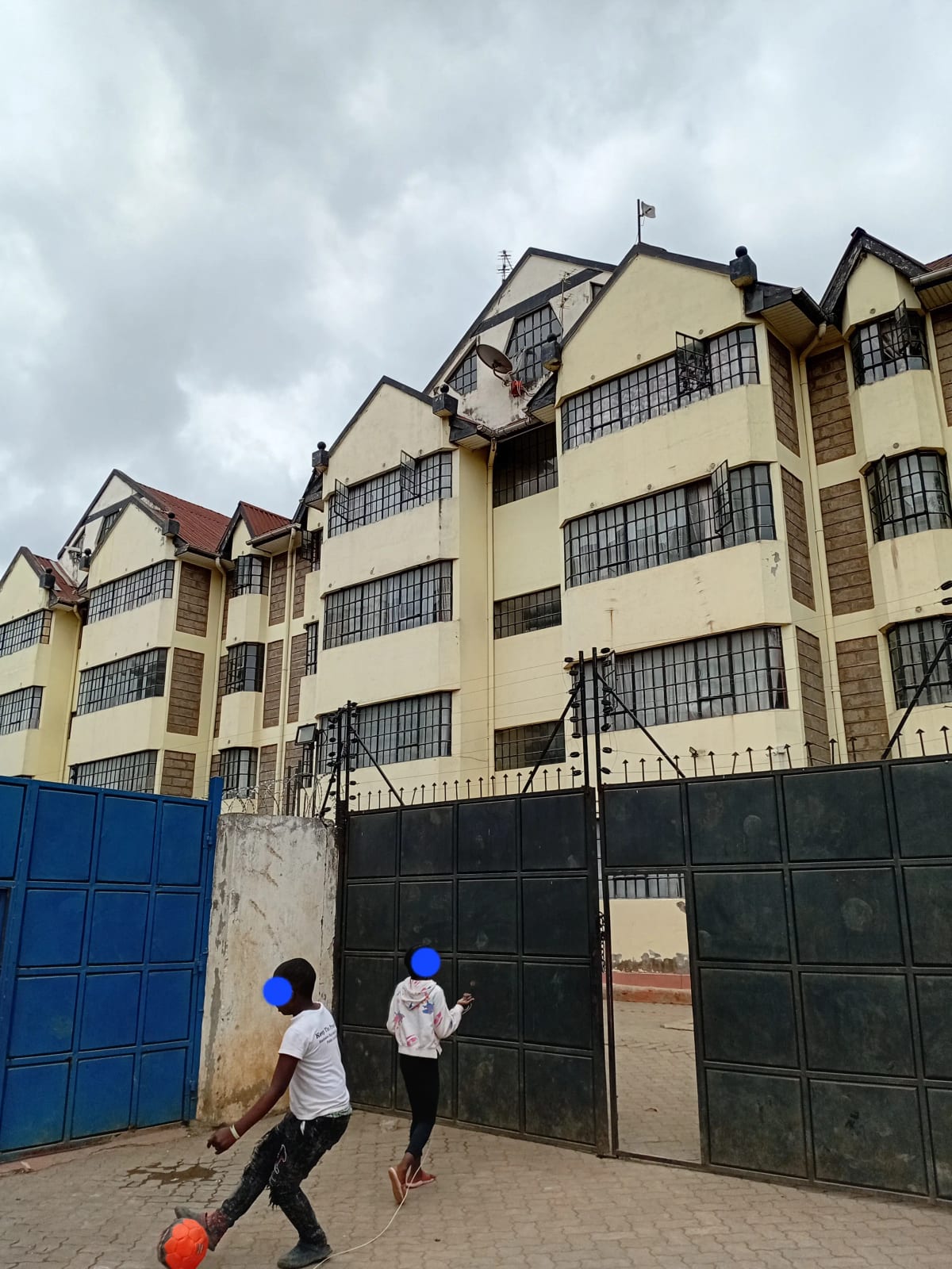 Multi-story residential building with yellow facade and security gates