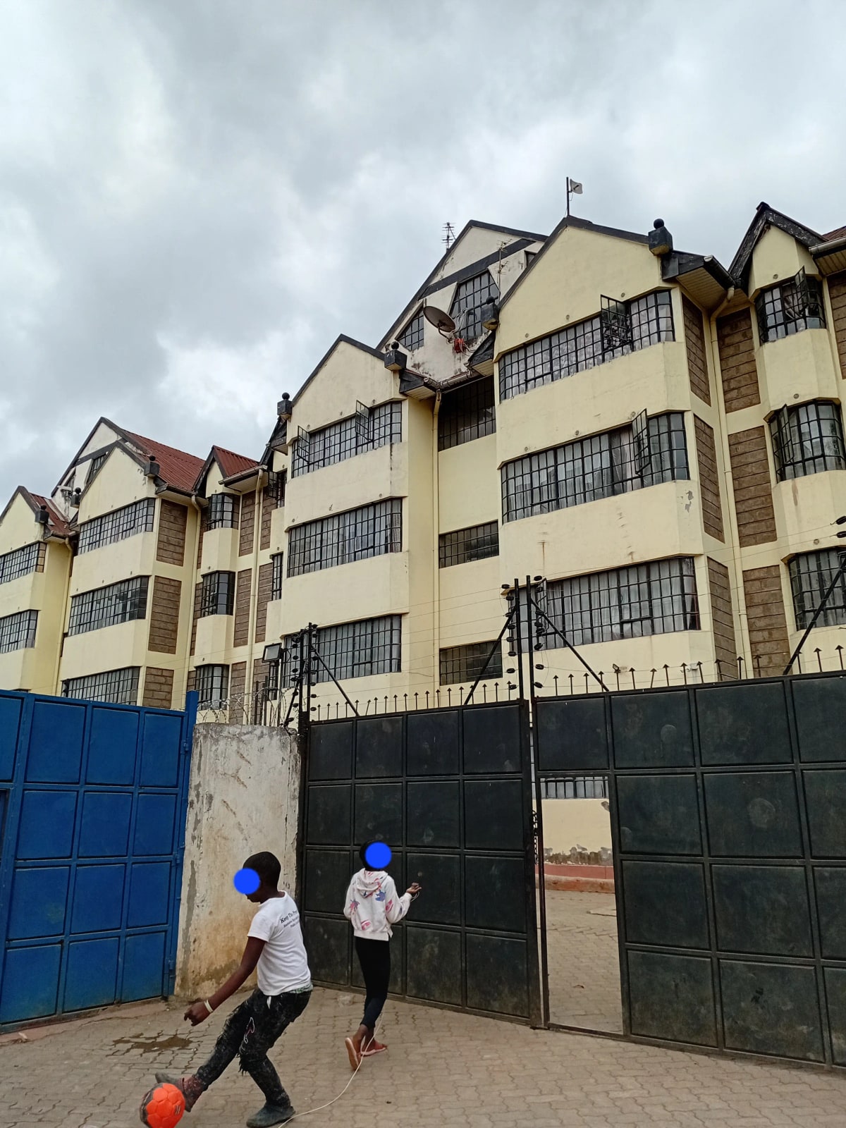 Multi-story residential building with yellow facade and security gates