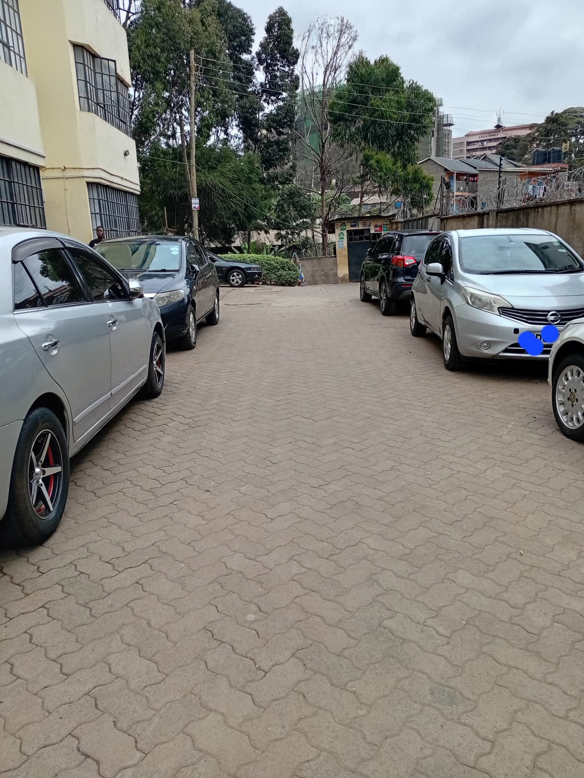 Paved compound parking area with multiple vehicles and building
