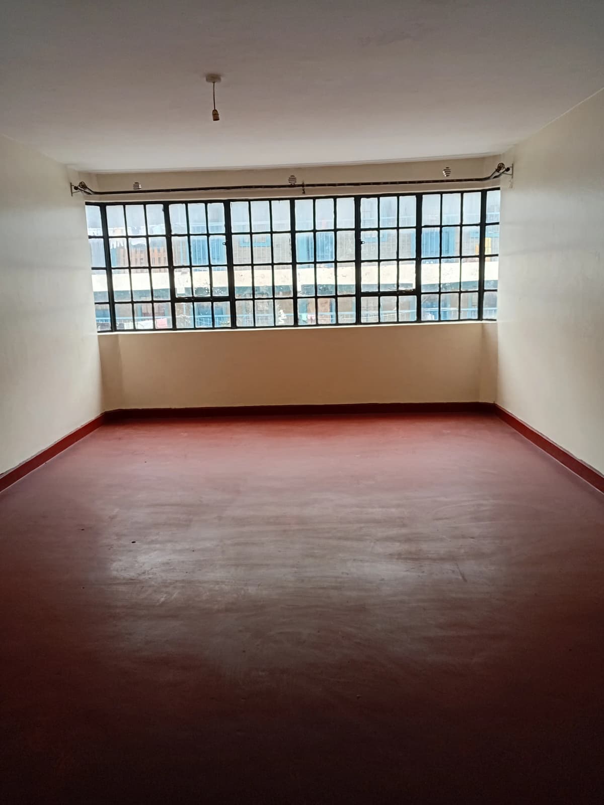 Spacious living room with large barred window and red floor