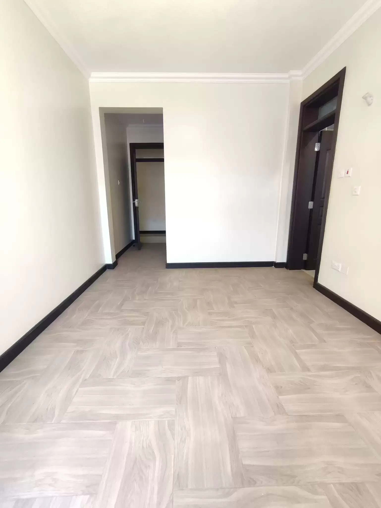 Empty bedroom with herringbone flooring and multiple doors