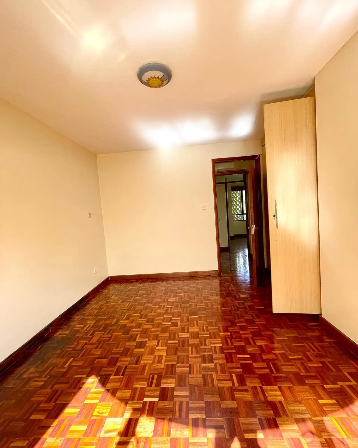 Empty corridor with herringbone parquet flooring and recessed lighting