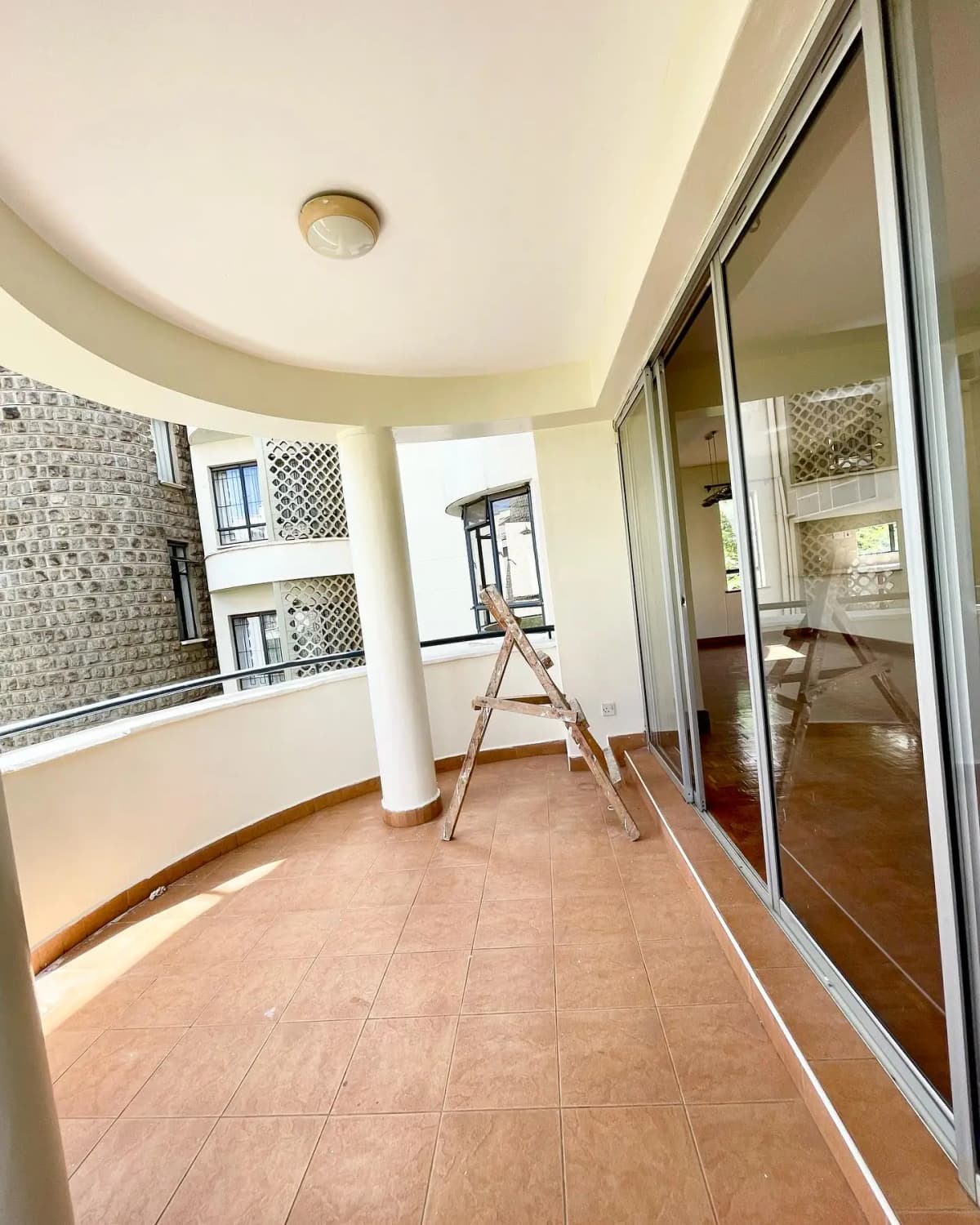 Spacious curved balcony with terracotta tiles and sliding doors