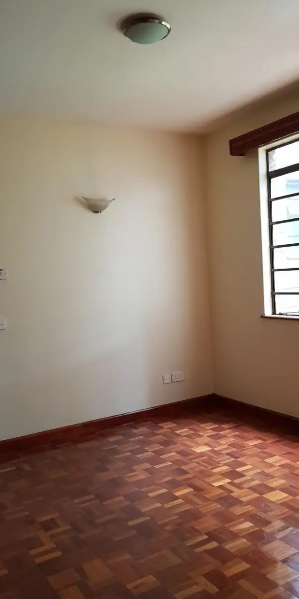 Empty bedroom with wooden floor and louvered window