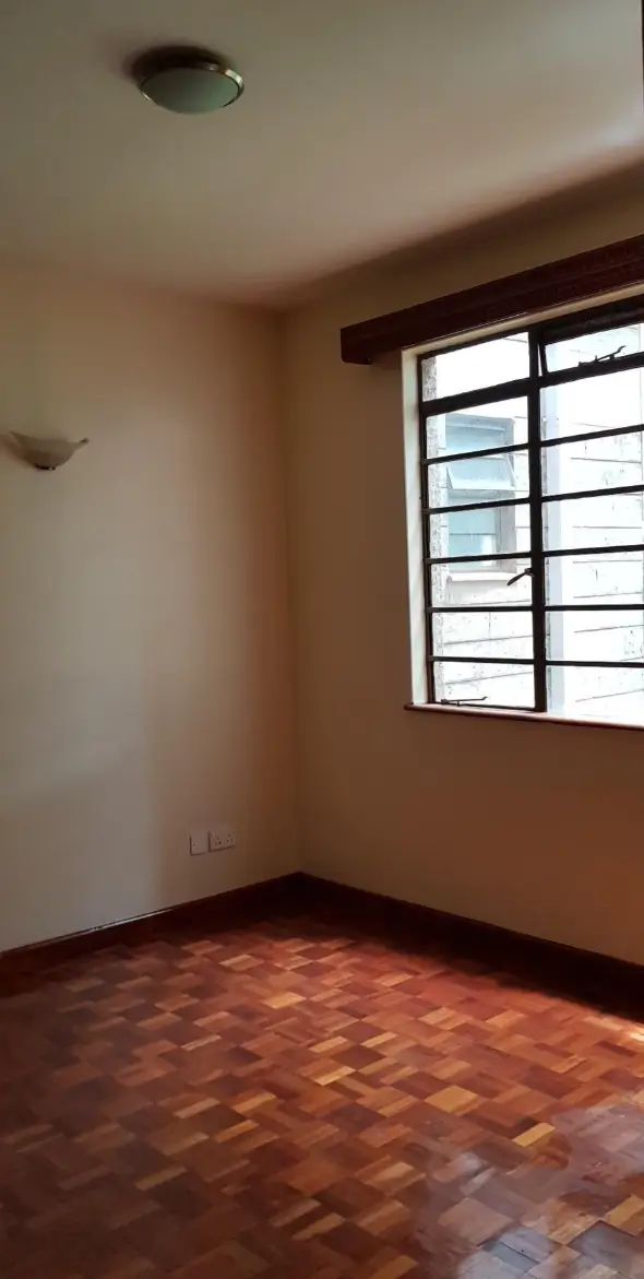 Empty bedroom with wooden floor and barred window