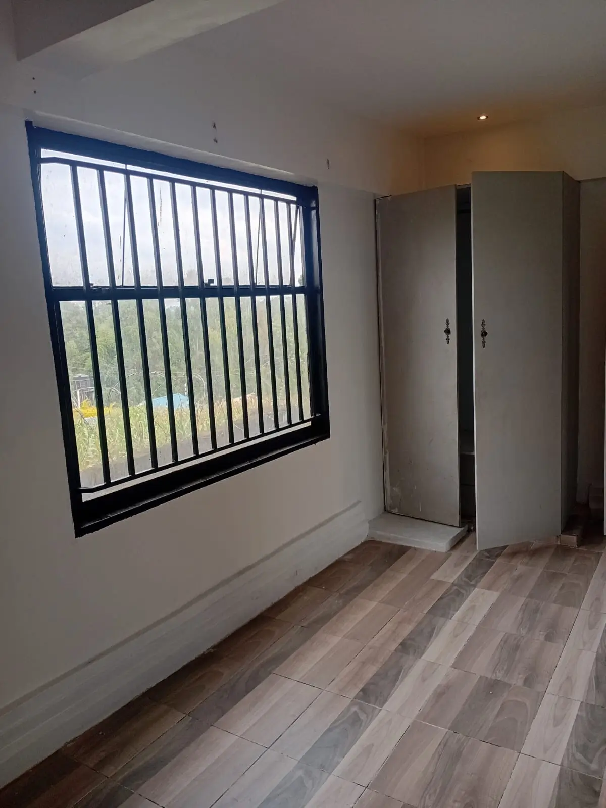 Bedroom with barred window, wooden flooring, built-in wardrobes
