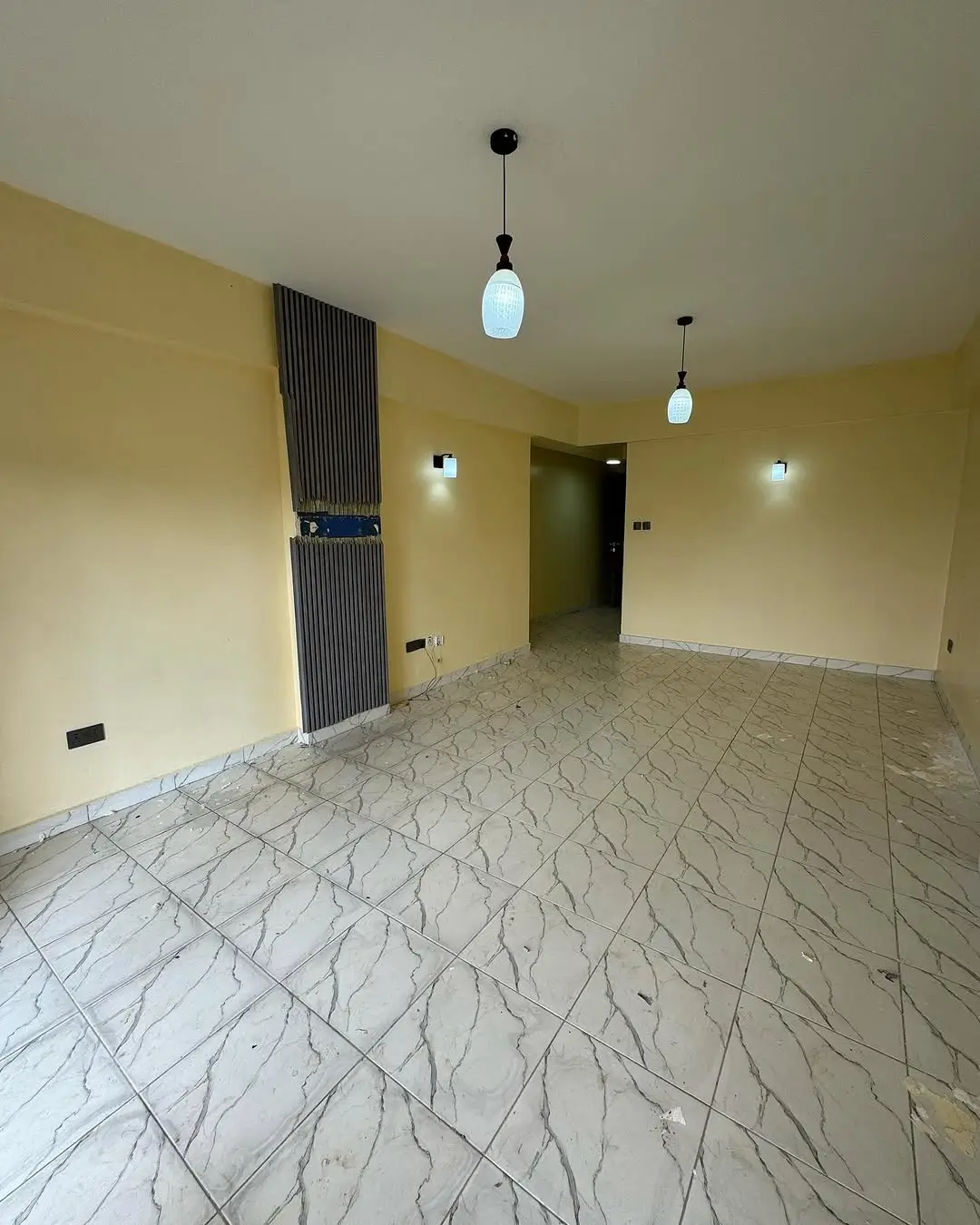Spacious living area with marble flooring and pendant lighting