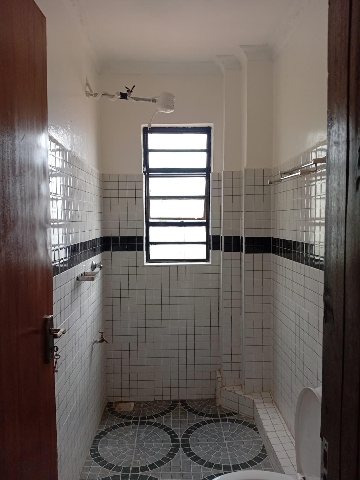 Compact bathroom with small window, tiled walls, dark stripe accent