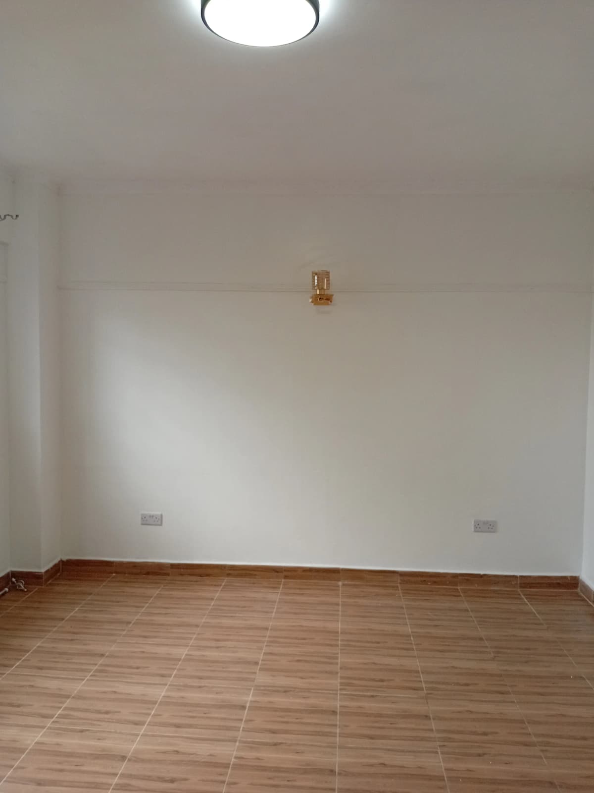 Empty bedroom with wooden flooring and ceiling light fixture