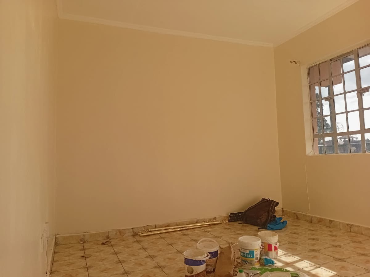 Empty bedroom with bare walls, tile flooring, large window