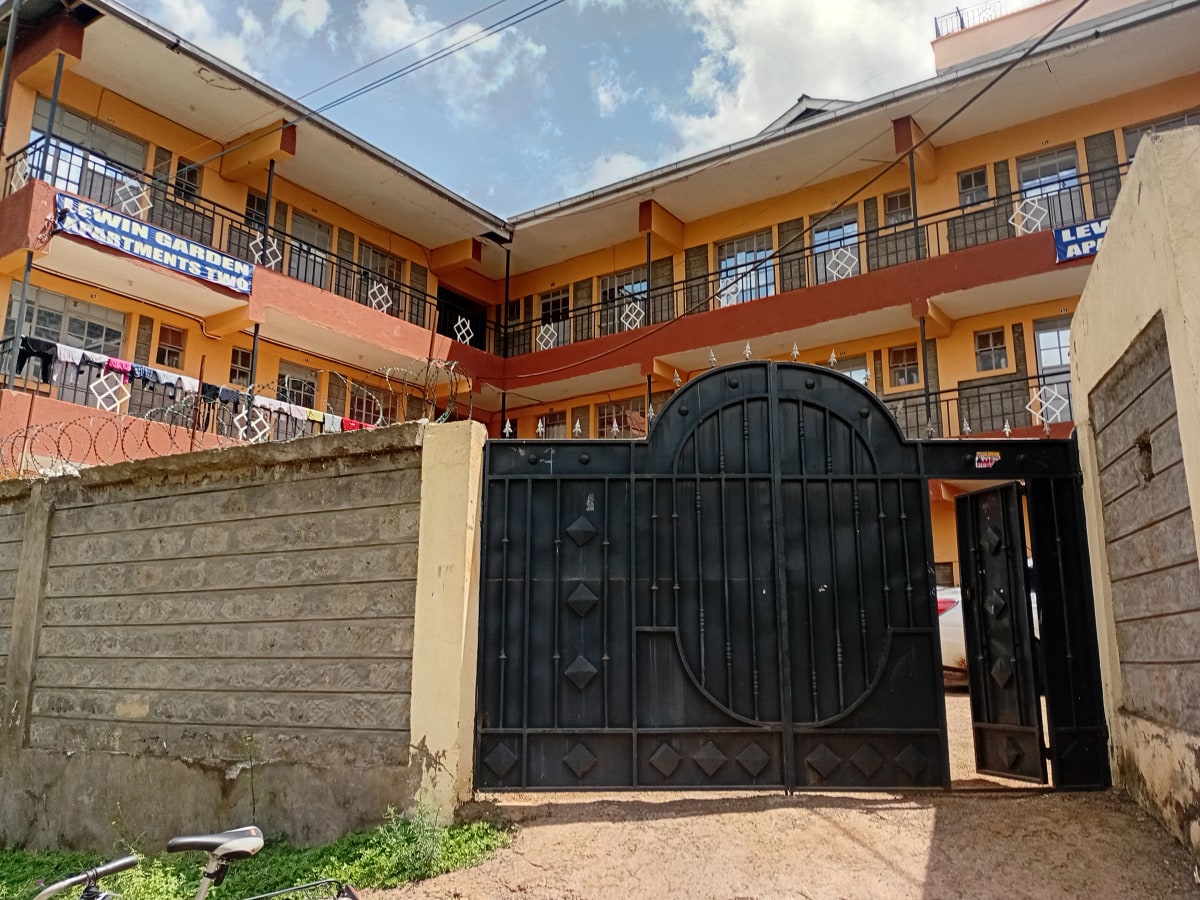 Multi-story residential building with orange facade and black gate