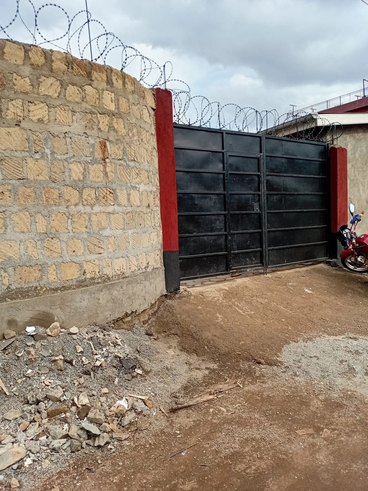 Compound entrance with black metal gate and stone wall