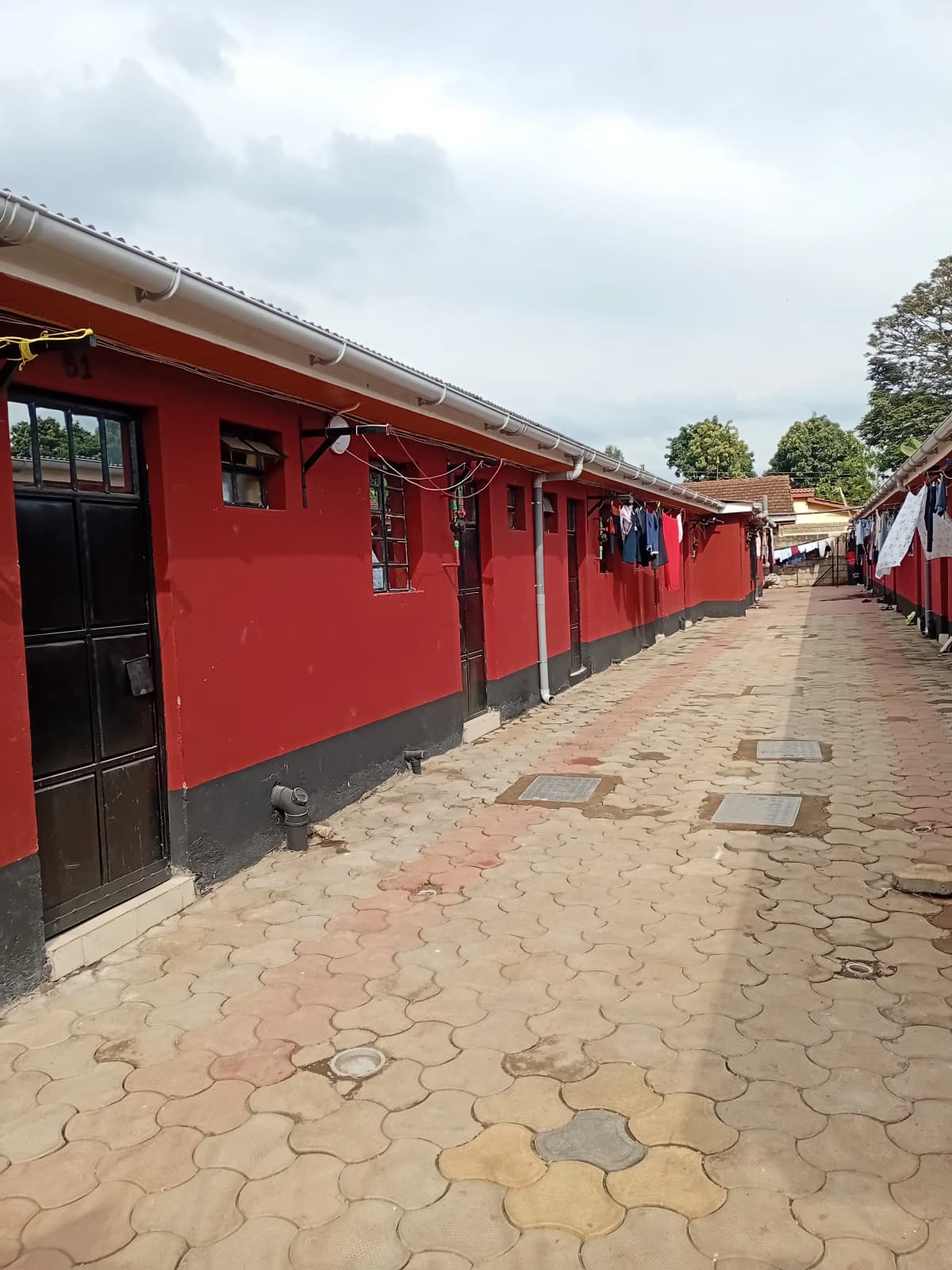 Red-painted residential building exterior with paved compound