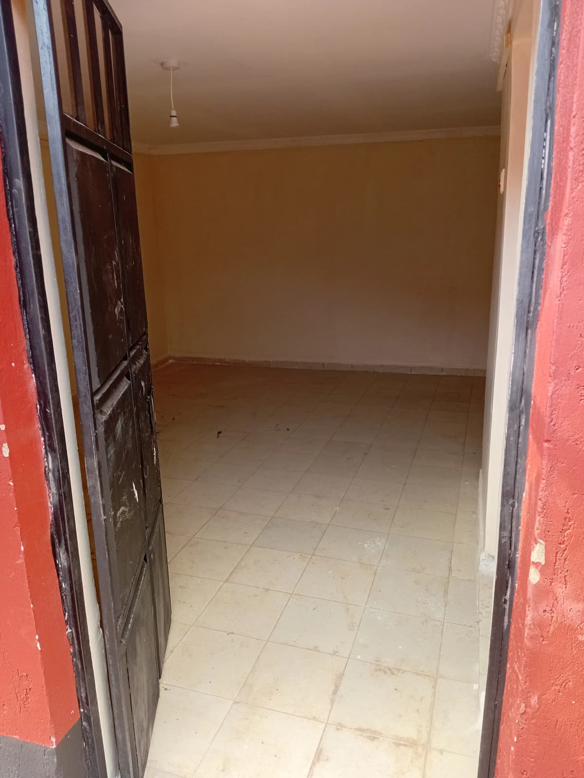 Empty bedroom with tiled flooring and wooden door frame