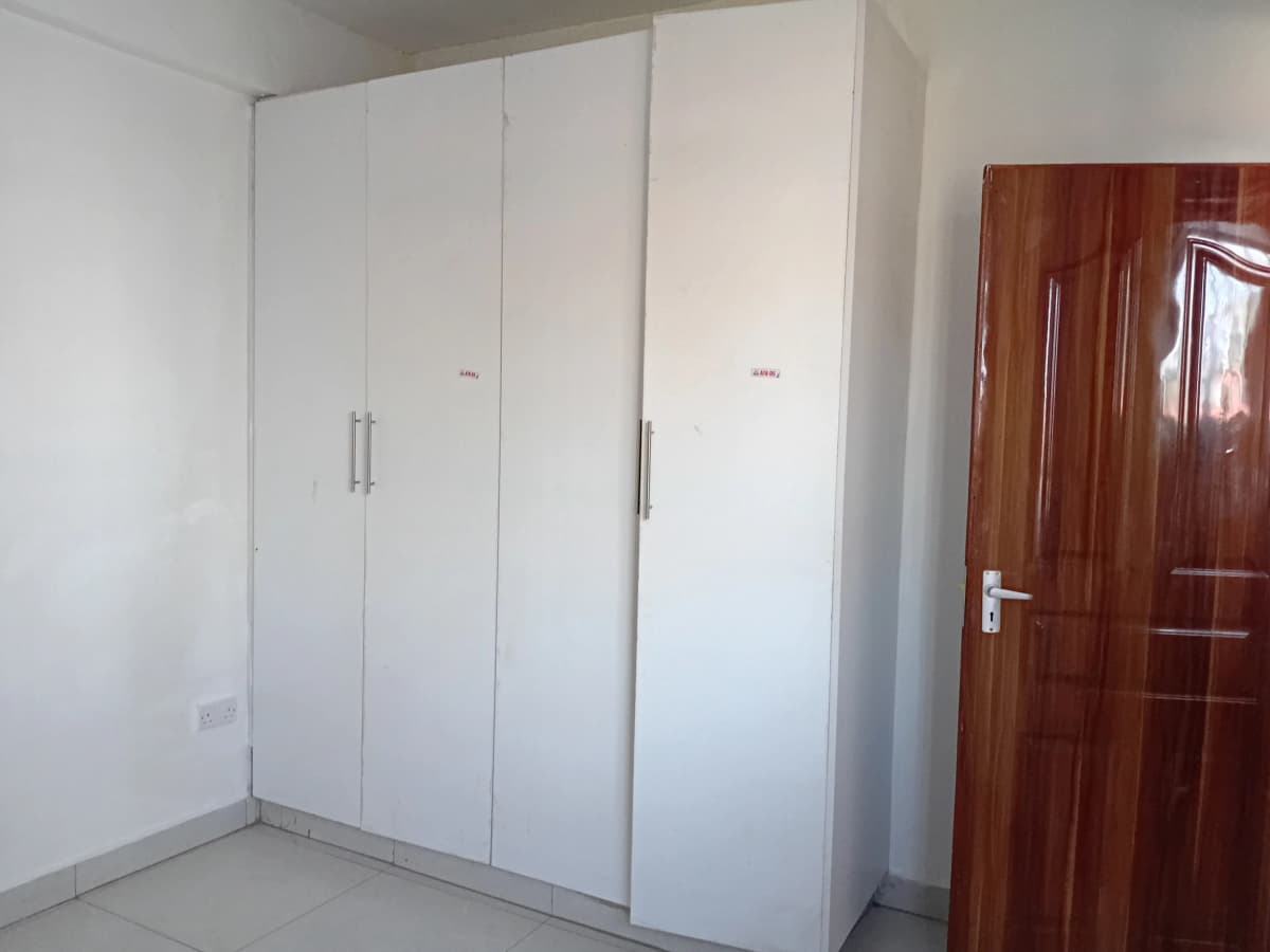 Empty bedroom with built-in white wardrobes and wooden door