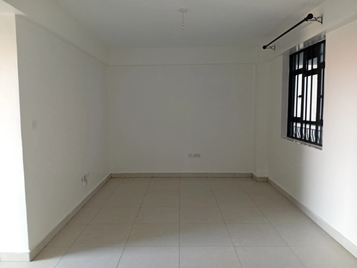 Empty living room with tiled flooring and barred window