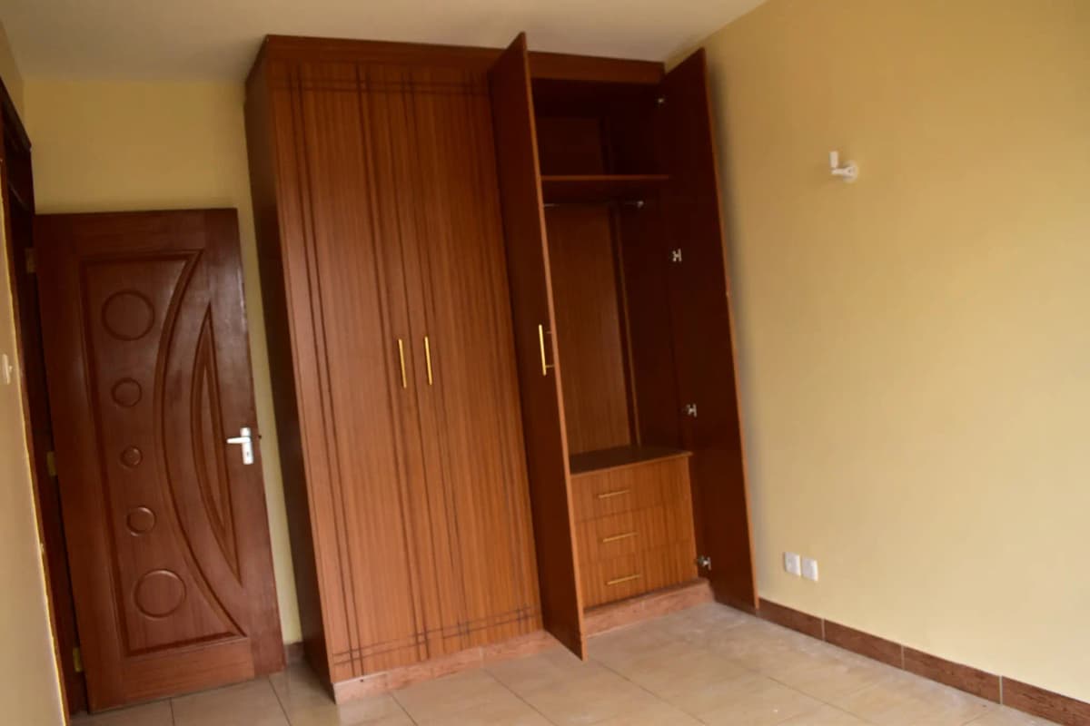 Unfurnished bedroom with wooden wardrobe and cream walls