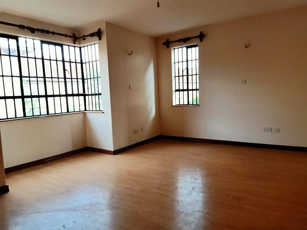 Spacious living room with wooden floors and barred windows