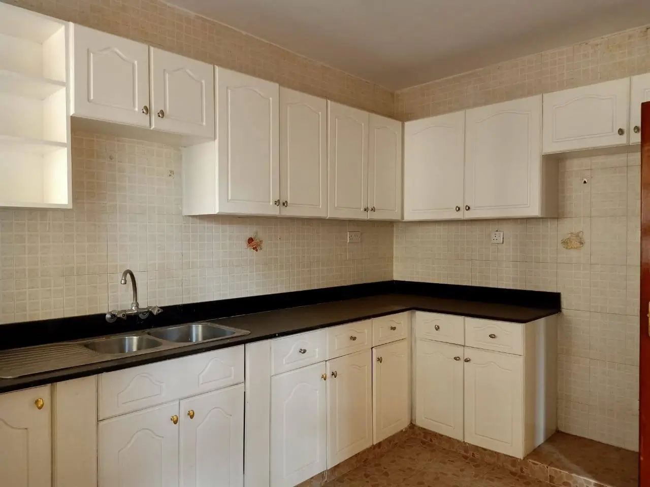 Cream cabinetry kitchen with black countertops and tiled backsplash