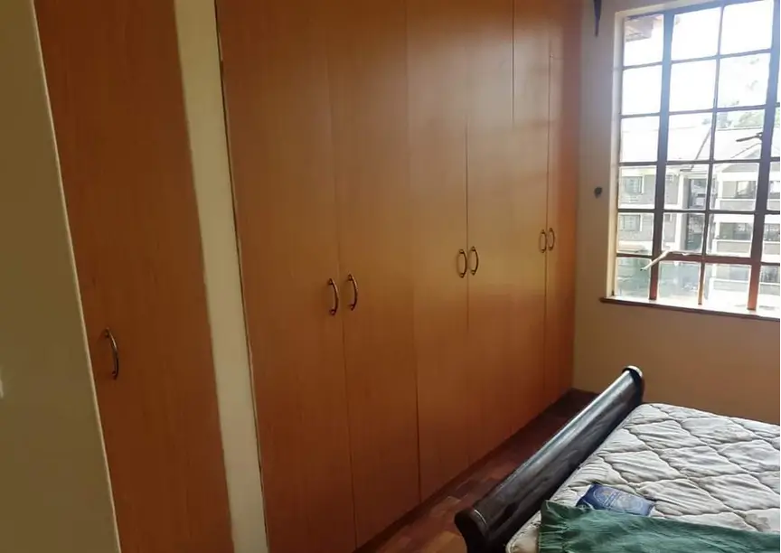 Bedroom with wooden built-in wardrobes and window view