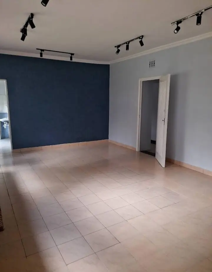 Spacious empty living room with accent wall and track lighting