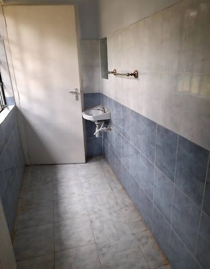 Compact bathroom with blue tile walls and basic fixtures