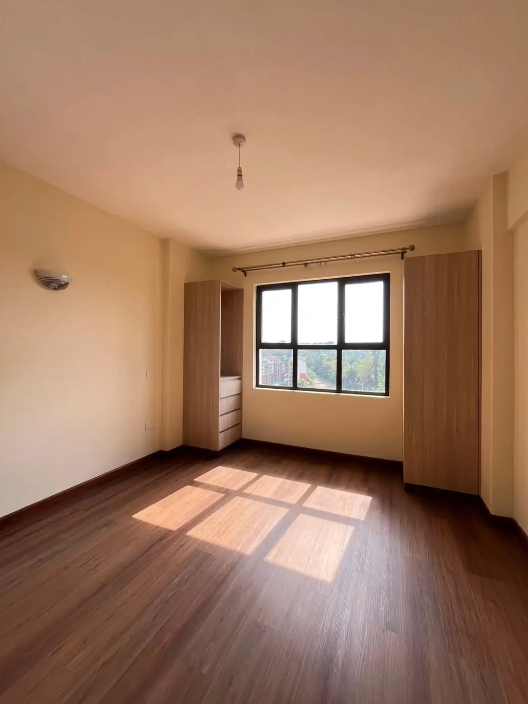 Bright bedroom with wood flooring and large window.