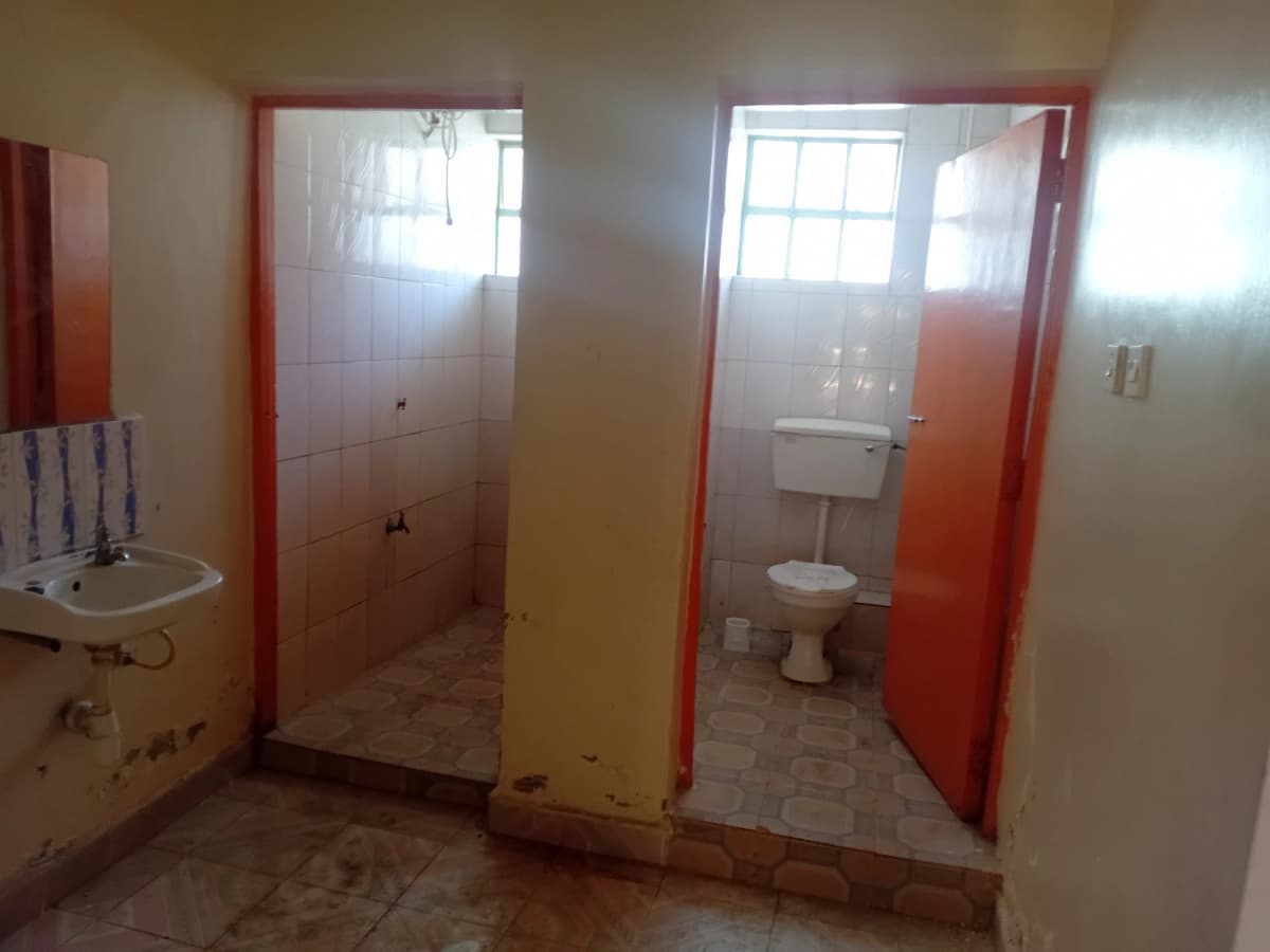 Shared bathroom facility with toilet, sink, shower stall
