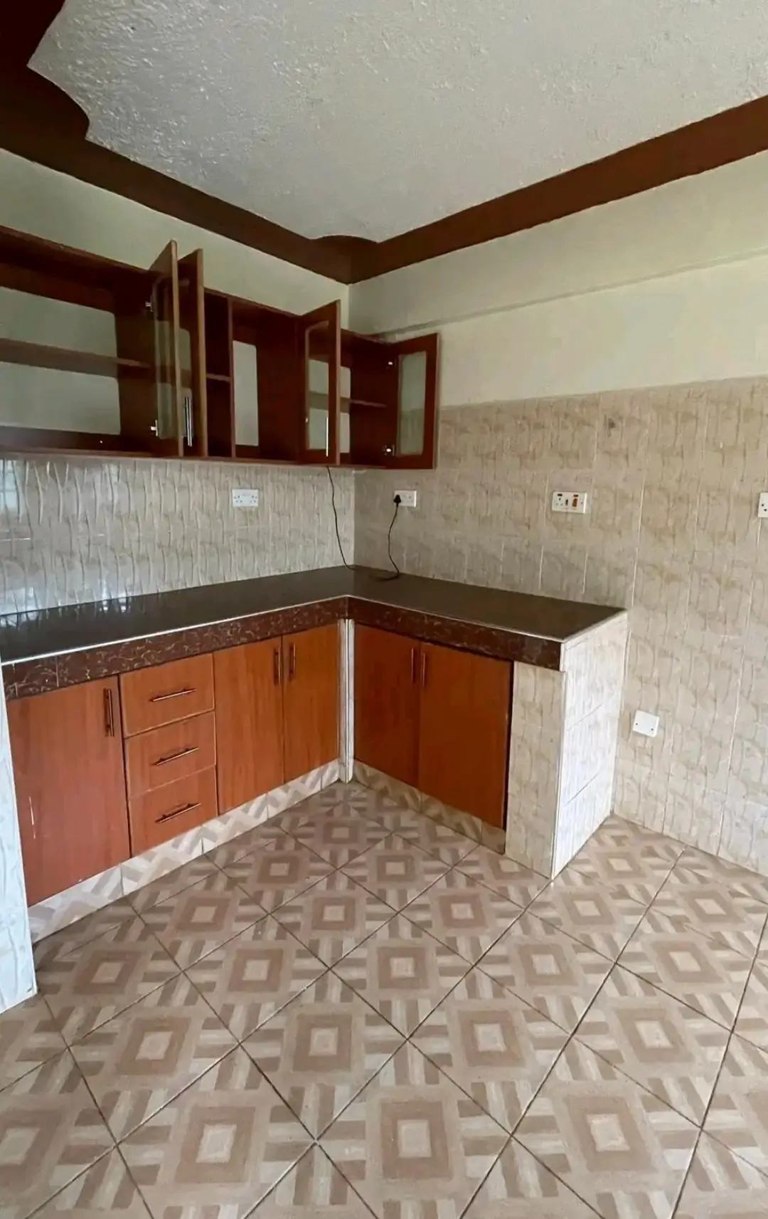 L-shaped kitchen with wooden cabinets and black countertops