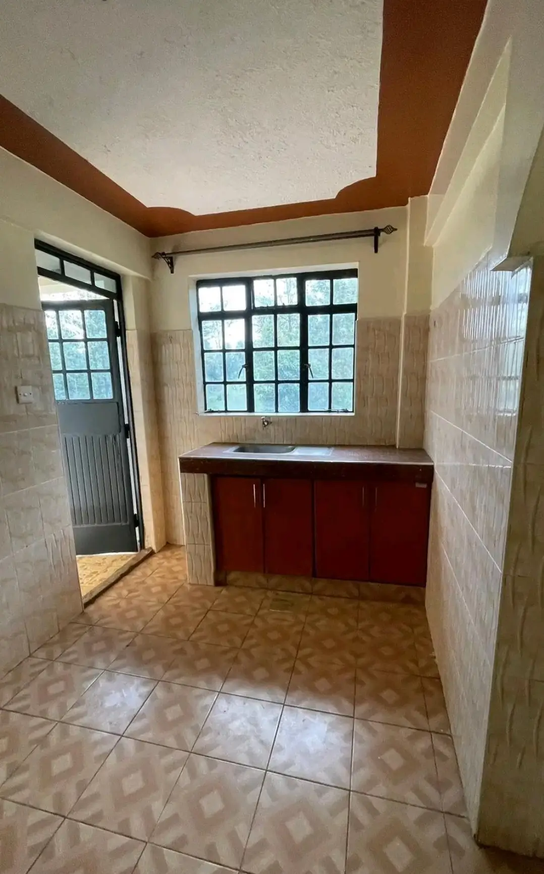 Compact kitchen with red cabinetry and tiled flooring